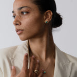 Woman wearing a necklace and earrings against a plain background