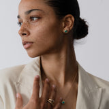 Woman wearing a necklace and earrings against a plain background